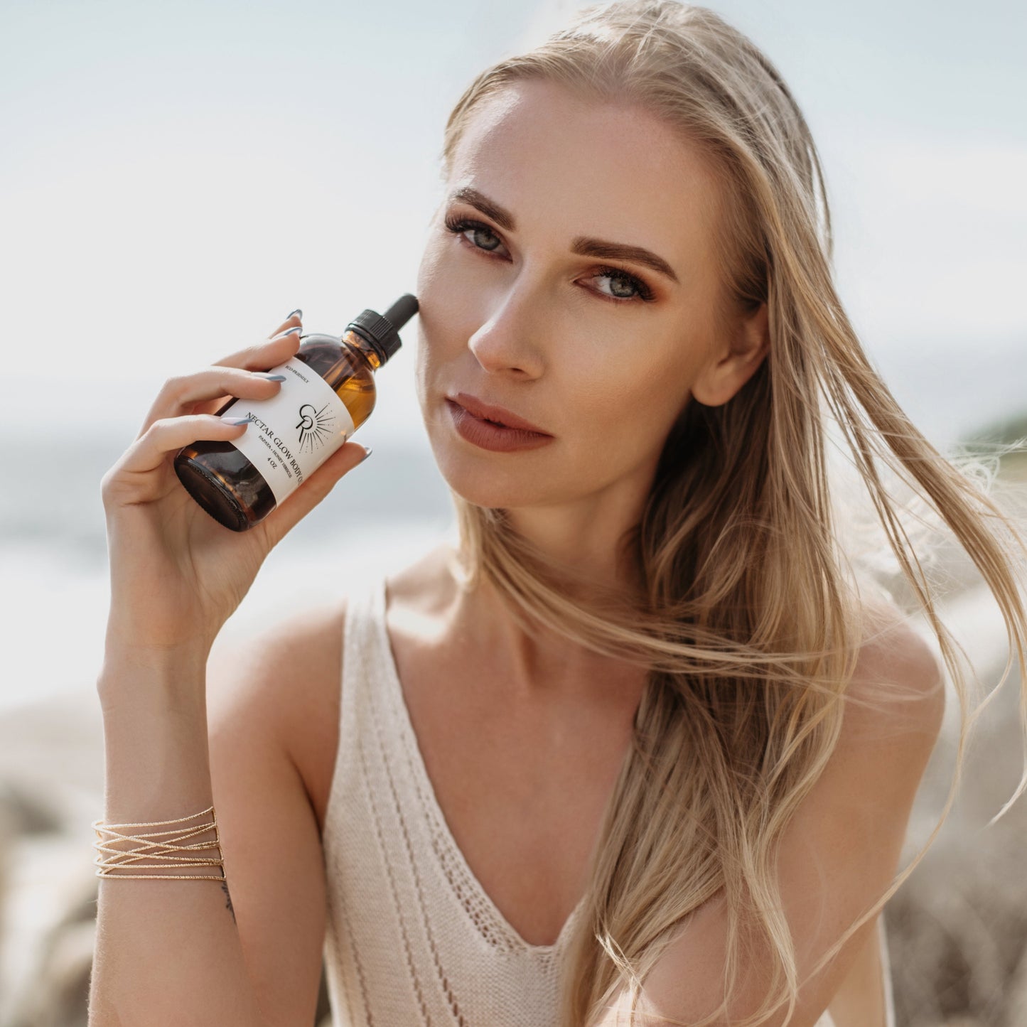 Woman applying Nectar Body Glow for dewy, radiant skin finish